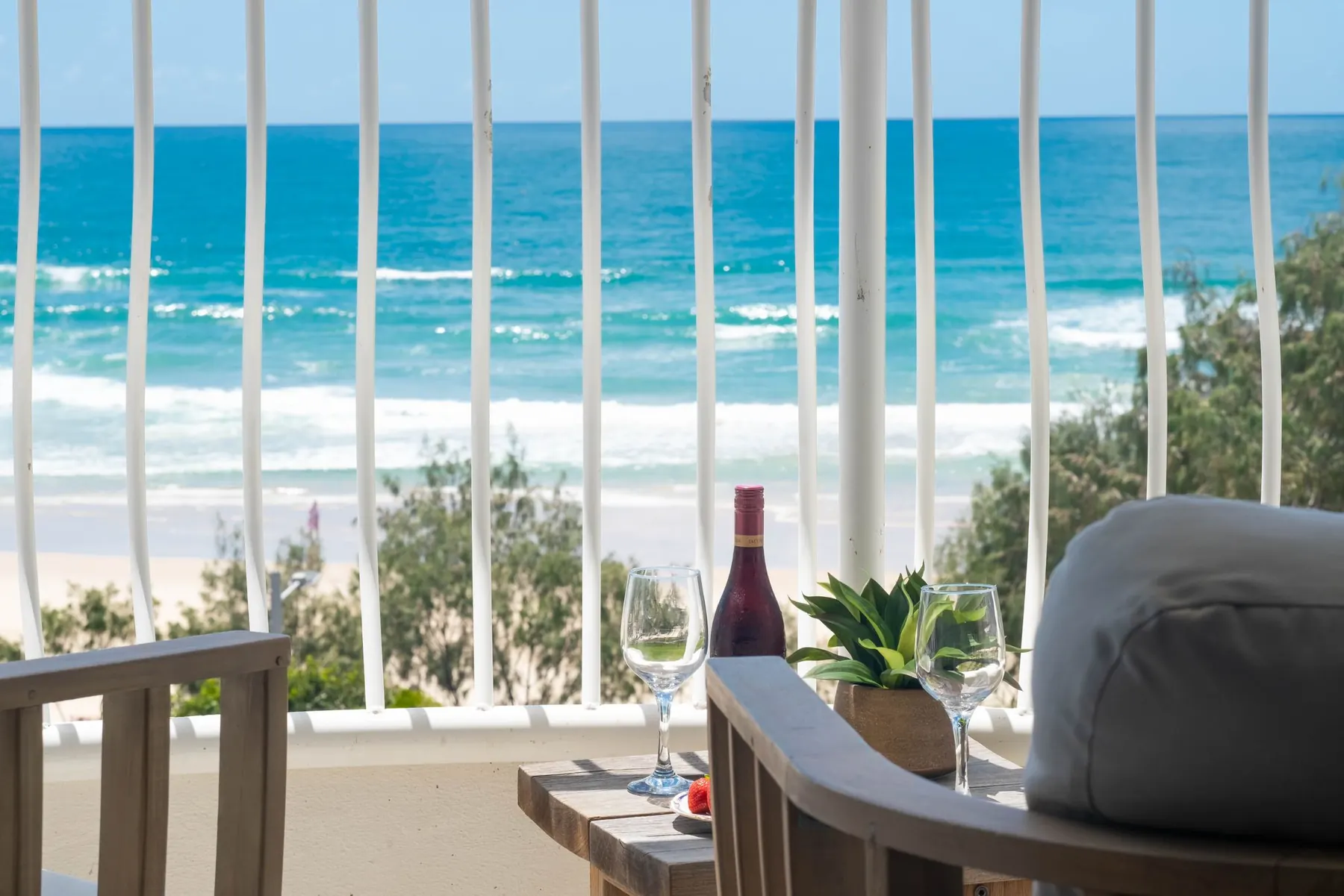 The balcony at Athena by the Sea, with drinks set out and the surf beyond